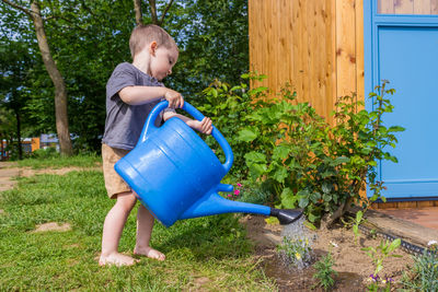 Side view of boy watering plants