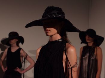 Portrait of woman wearing hat standing against wall