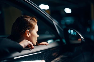 Side view of young woman sitting in car