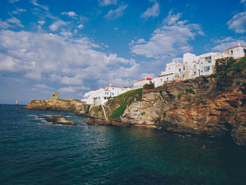 Buildings by sea against sky