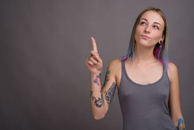 Portrait of young woman standing against wall