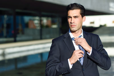 Portrait of businessman adjusting tie