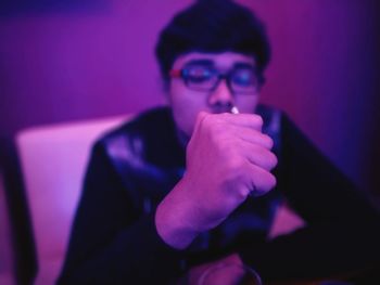 Close-up of man gesturing fist while sitting on chair in darkroom