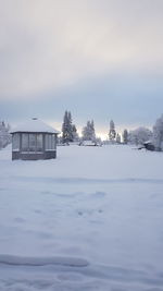 Scenic view of snow covered house and buildings against sky