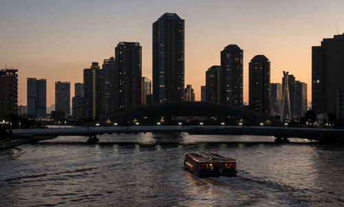 Buildings by river against sky in city