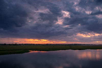 Scenic view of dramatic sky over lake during sunset