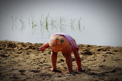 Girl bending on land against lake