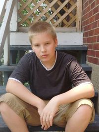 Portrait of young man sitting on wall