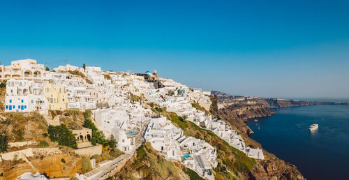 High angle view of townscape by sea against clear blue sky