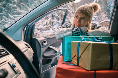 Woman giving gifts is holding presents delivering to home car holidays concept sunny cold winter day