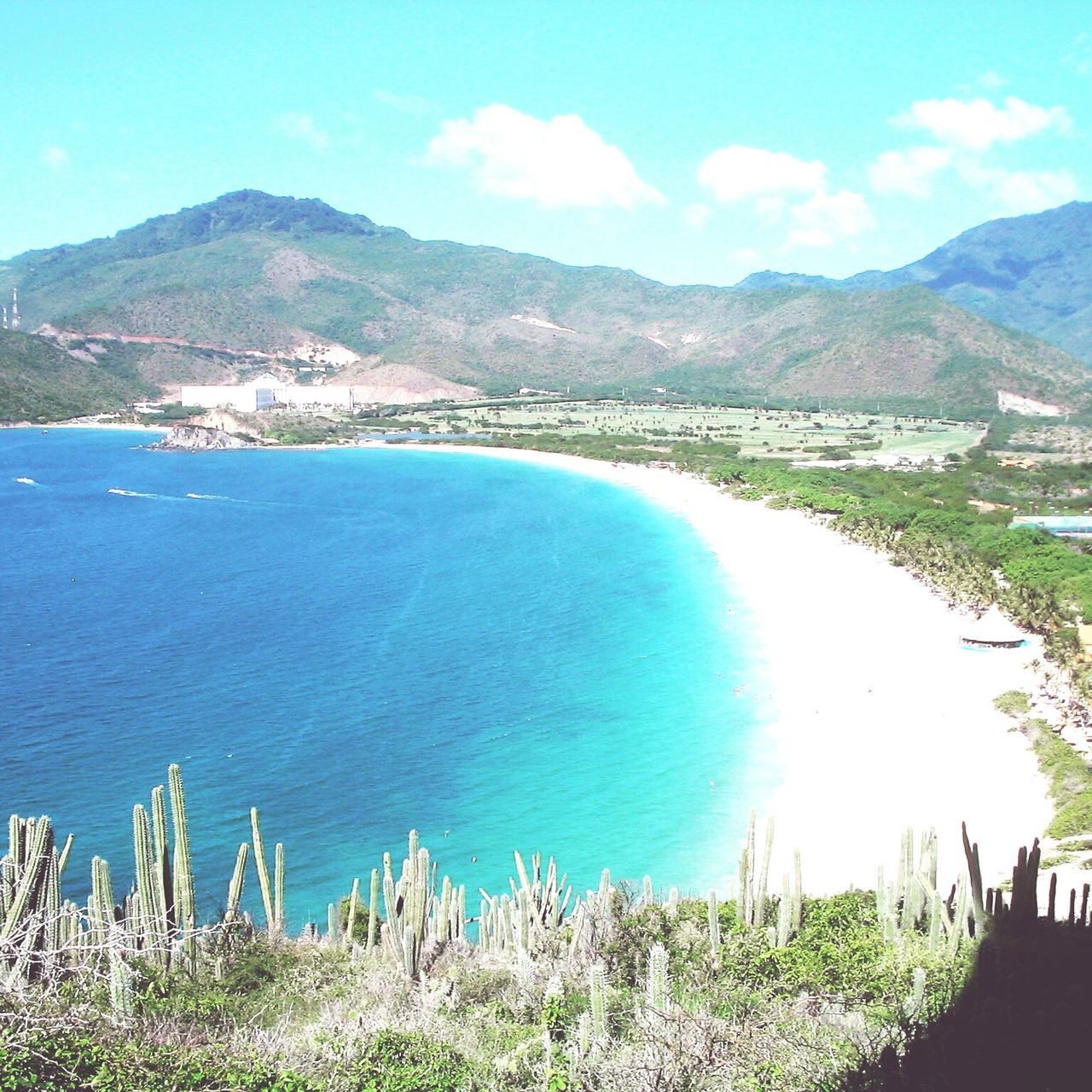 water, sea, mountain, blue, scenics, tranquil scene, beach, tranquility, sky, beauty in nature, coastline, mountain range, shore, high angle view, nature, grass, landscape, sand, idyllic, plant