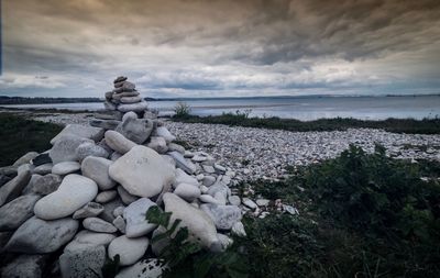 Stack of pebbles on beach against sky