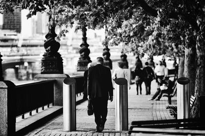 Full length rear view of businessman walking on sidewalk in city