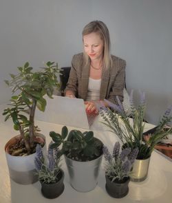 Woman looking at potted plant on table