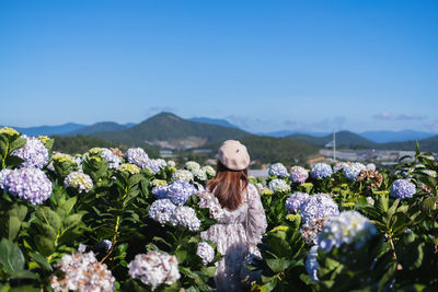 Woman with pink flowers against blue sky