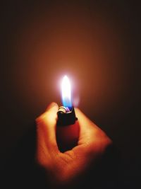 Close-up of hand holding lit candle