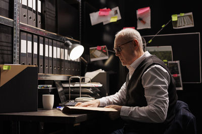 Side view of man using mobile phone while sitting in office