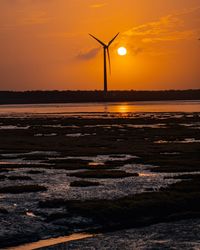 Silhouette of wind turbine against sky during sunset