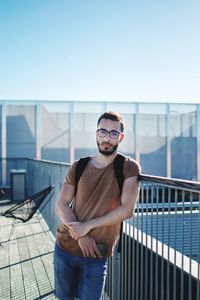 Portrait of young man standing against railing