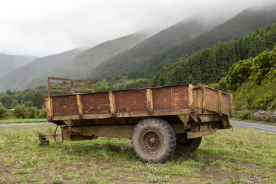 Abandoned truck on field against mountains
