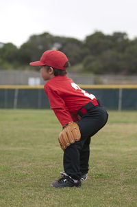 Young boy with his hands and glove on his kees on a baseball field