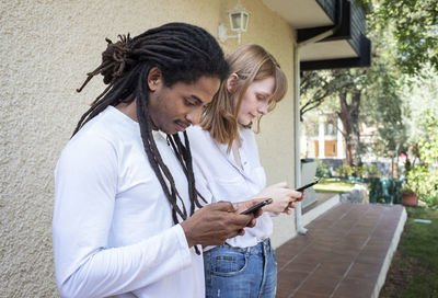 Young woman using mobile phone while standing on laptop