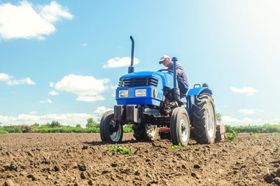 The farmer works on a tractor. loosening the surface, cultivating the land for further planting. 