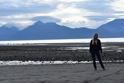 Full length of woman standing on snowcapped mountain against sky