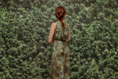 Rear view of woman standing against plants