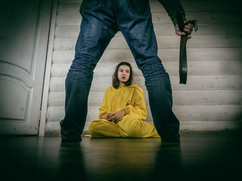 Young woman sitting against wall