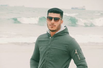 Young man wearing sunglasses standing at beach