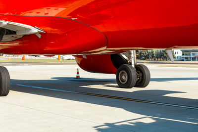 Red airplane with wheels on the ground, seen on the runway