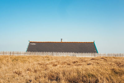 Built structure on field against clear blue sky