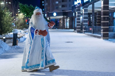 Russian santa claus carries a christmas tree outdoors