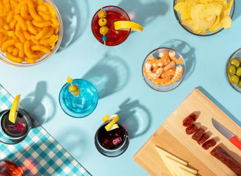 Blue table set with various snacks, appetizers and cocktails