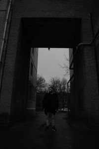 Rear view of woman walking in alley amidst buildings