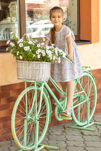 Portrait of young woman with bicycle against wall