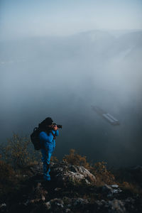 Man photographing on mountain against sky