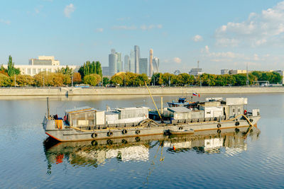 Boats moored in river against sky in city