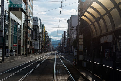 Railroad tracks amidst buildings on sunny day in city