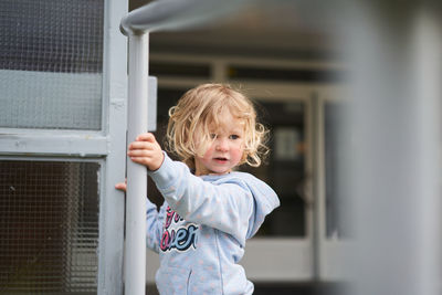 Portrait of cute girl standing against wall