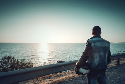 Rear view of man looking at sea against sky