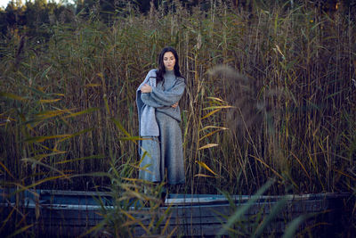 Woman stands in a gray sweater and skirt next to the lake in the fall