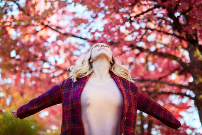 Low angle view of young woman against autumn tree