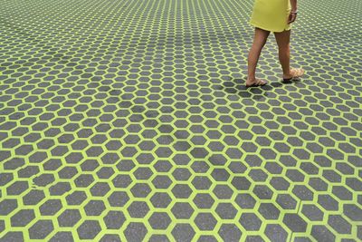 Low section of woman walking on patterned pavement