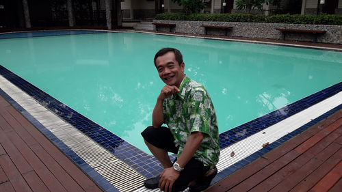 Portrait of man crouching at swimming pool