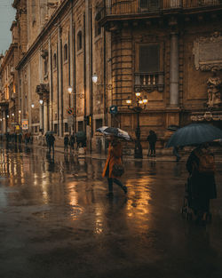 People walking on wet street during rainy season