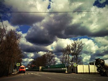 Cars on road against cloudy sky