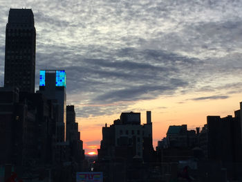 Buildings in city against cloudy sky