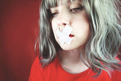 Close-up of sad woman with tape on her mouth